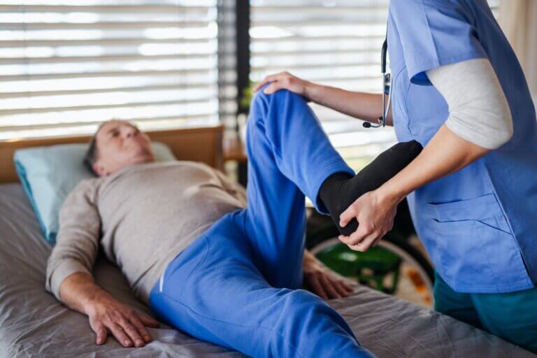 A healthcare worker and senior patient in hospital, physiotherapy.