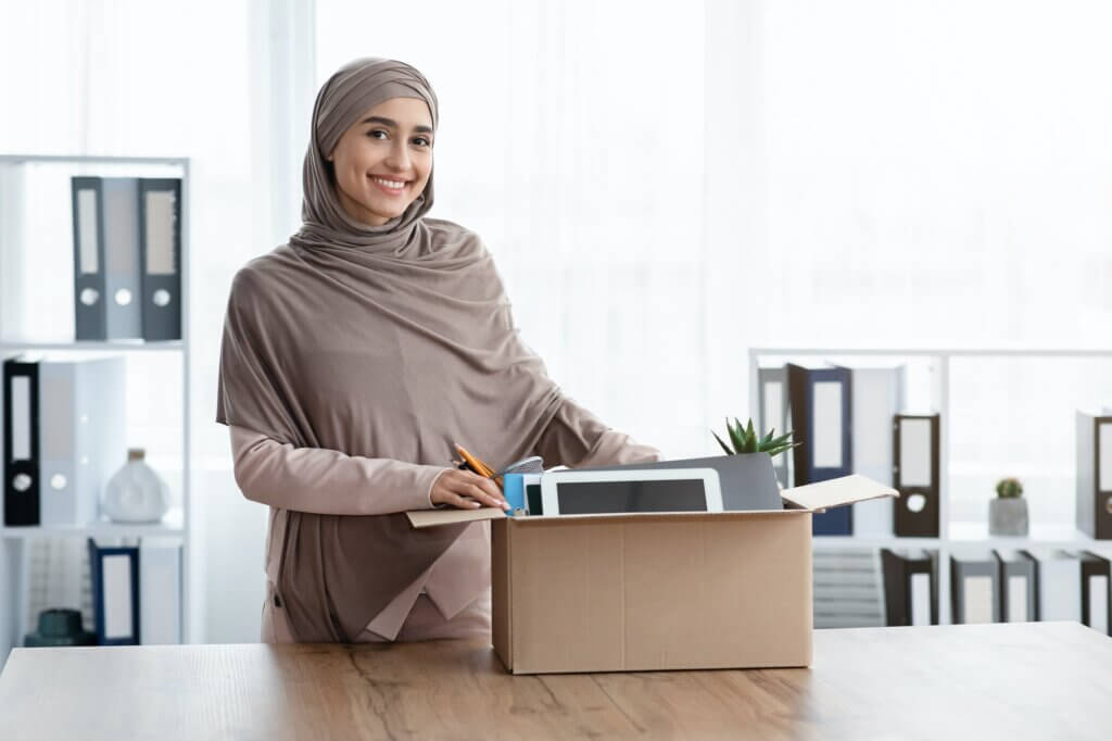 Happy Woman Standing Near Box With Her Belongings In New Office