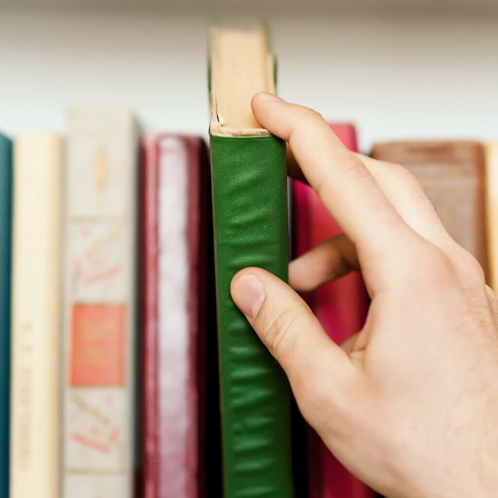 Here is a book I need. Close-up of someone taking a book from the book shelf
