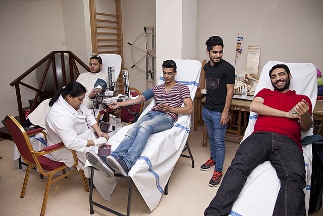 Students seated at tables while health professionals conduct a supervised health activity on campus