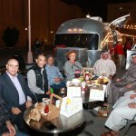 A group of people sitting around a table with food Description automatically generated with medium confidence